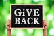 Person holding up a chalkboard that says "Give Back" [Image by creator christianchan from AdobeStock]