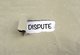 Image of a ripped piece of brown paper exposing a white background and the word "dispute" [Image by creator tumsasedgars from AdobeStock]