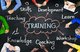 A blackboard with the word "TRAINING" in the middle, surrounded by a pink cloud with arrows pointing to words including teaching, skills, development, knowledge, coaching, workshop, and learn [Image by creator Rawpixel.com from AdobeStock]